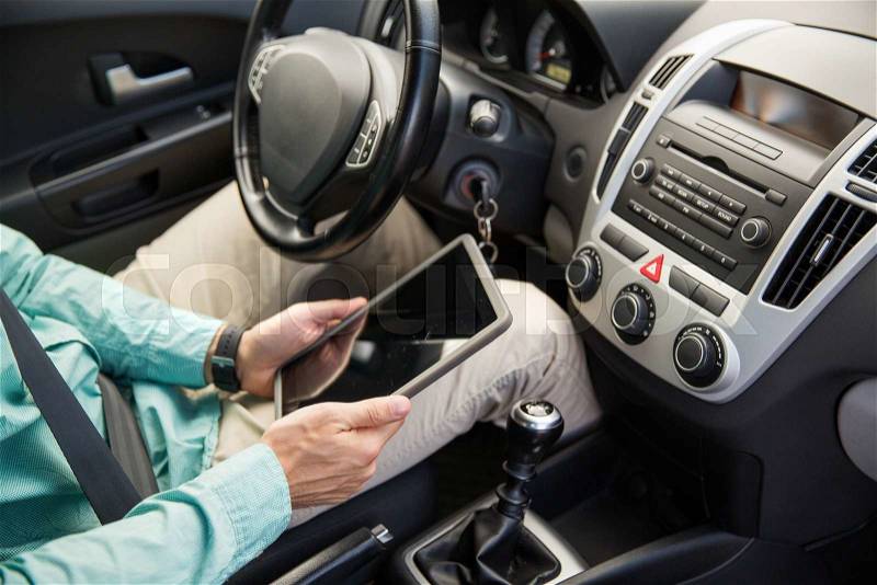 Transport, business trip, technology and people concept -close up of young man with tablet pc computer driving car, stock photo