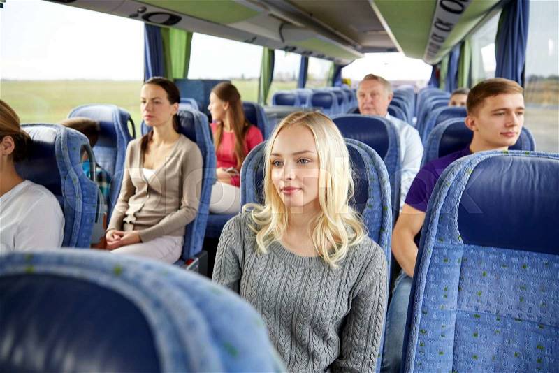 Transport, tourism, road trip and people concept - young woman with group of passengers or tourists in travel bus, stock photo