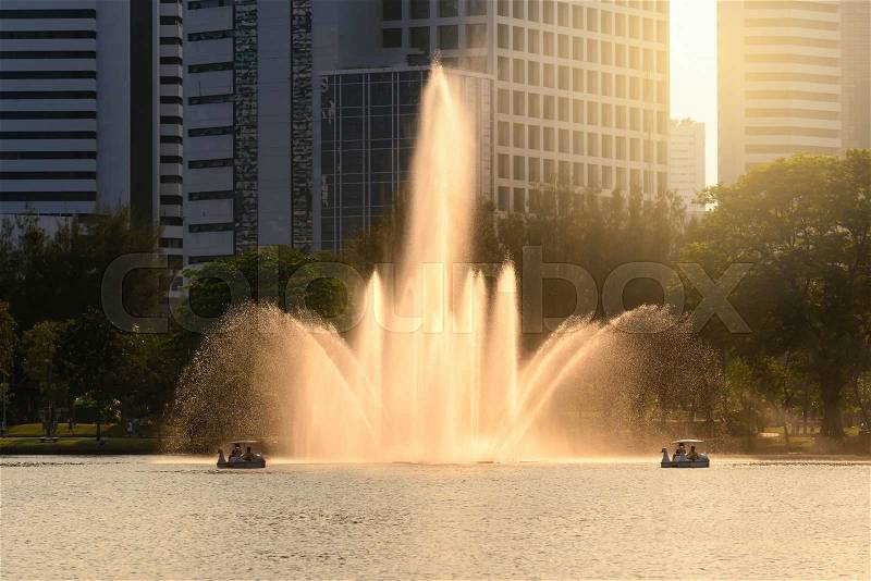 Beautiful fountain in urban lake with closeup building background, stock photo
