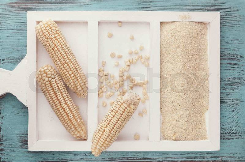 Dried white corn on the cob and corn flour on rustic background. Top view, blank space, vintage style, stock photo