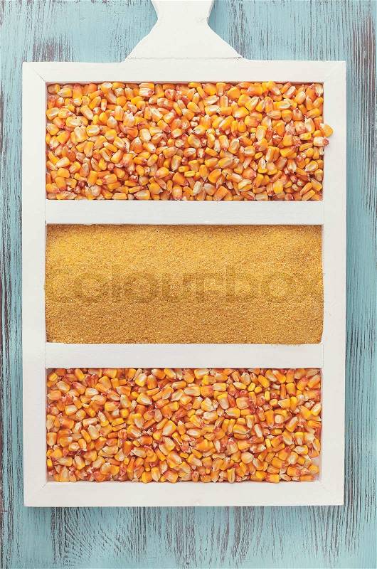 Corn kernels and cornmeal. Overhead shot of cornmeal with corn kernels on wooden board, stock photo