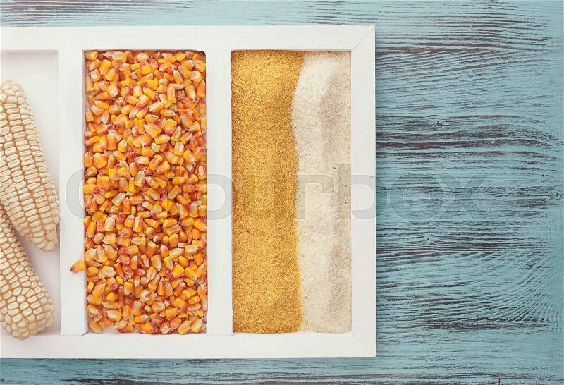 Cornmeal, corn seeds and corn cob on wooden background. Top view, vintage toned image, blank space, stock photo