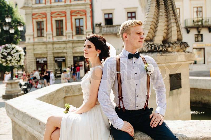 Bride and groom posing at the old fountain, stock photo