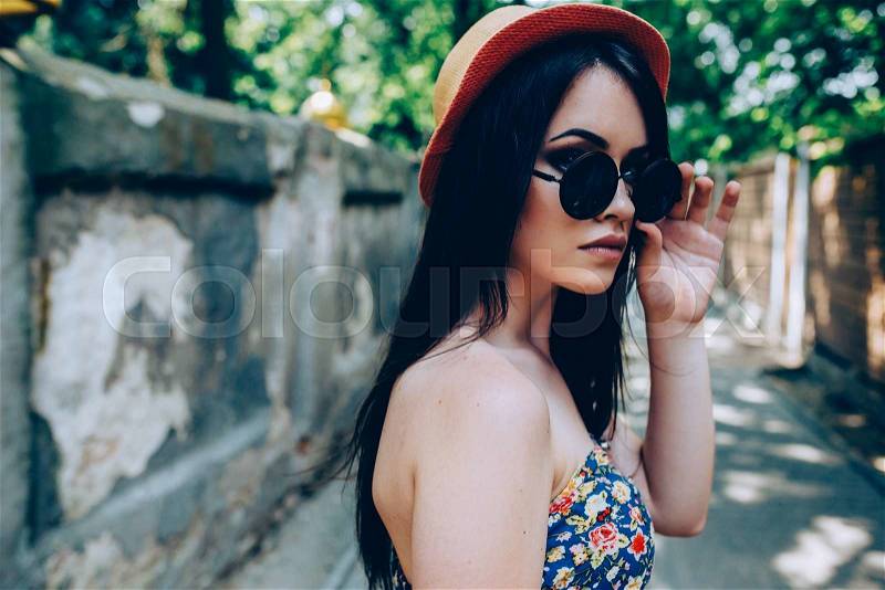 Beautiful girl in sunglasses posing for the camera in the city, stock photo
