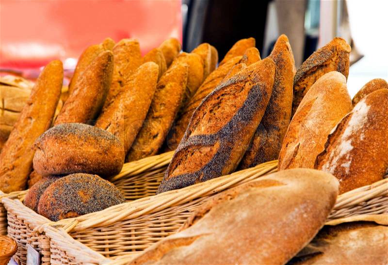 Various kinds of rustic bread in baskets being offered at a french market, stock photo