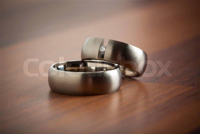 Silver wedding rings laying on table, focus on the diamond of the bride\'s ring, stock photo