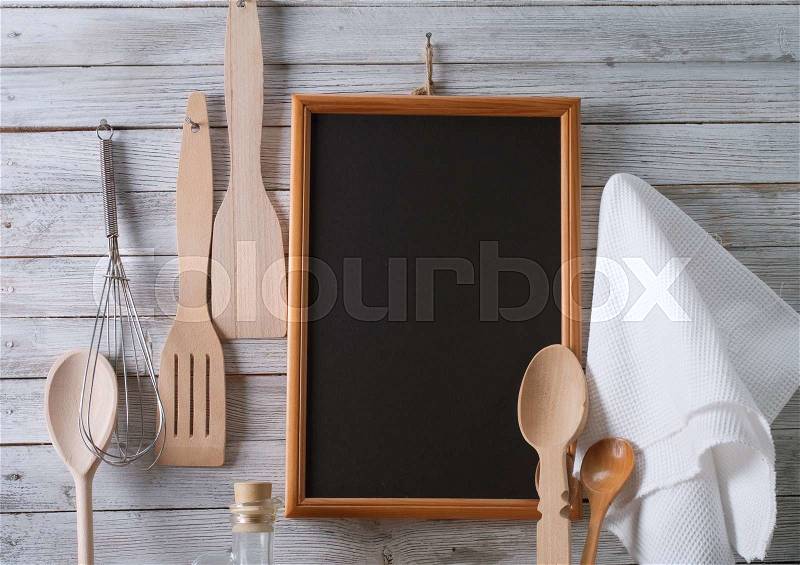 Blackboard on wooden surface and serving spoons, stock photo