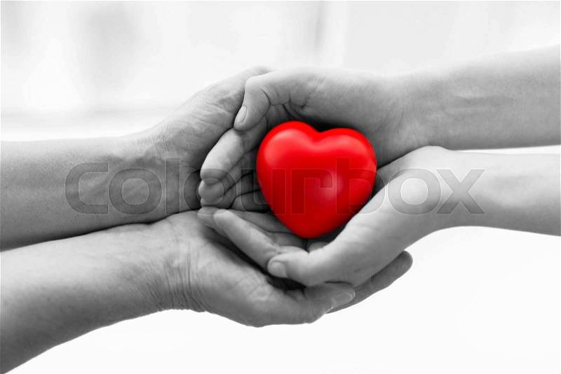 People, age, family, love and health care concept - close up of senior woman and young woman hands holding red heart, stock photo