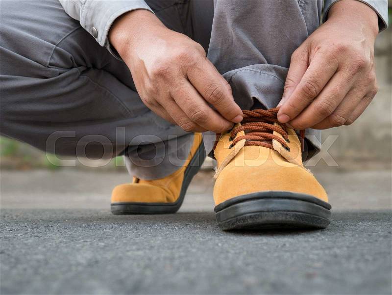 Close up of The man siting to wears safety shoes on street, stock photo