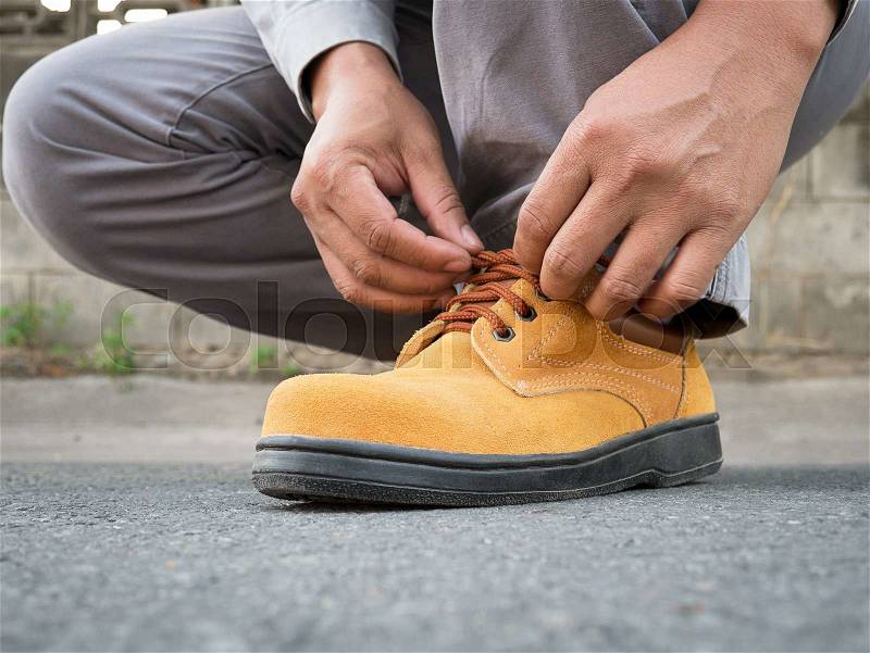 Close up of The man siting to wears safety shoes on street, stock photo