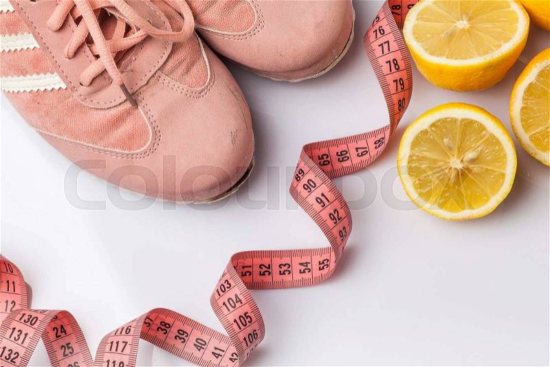 The old sneakers, a meter tape and lemon on an white. Concept of fitness and healthy lifestyle, stock photo