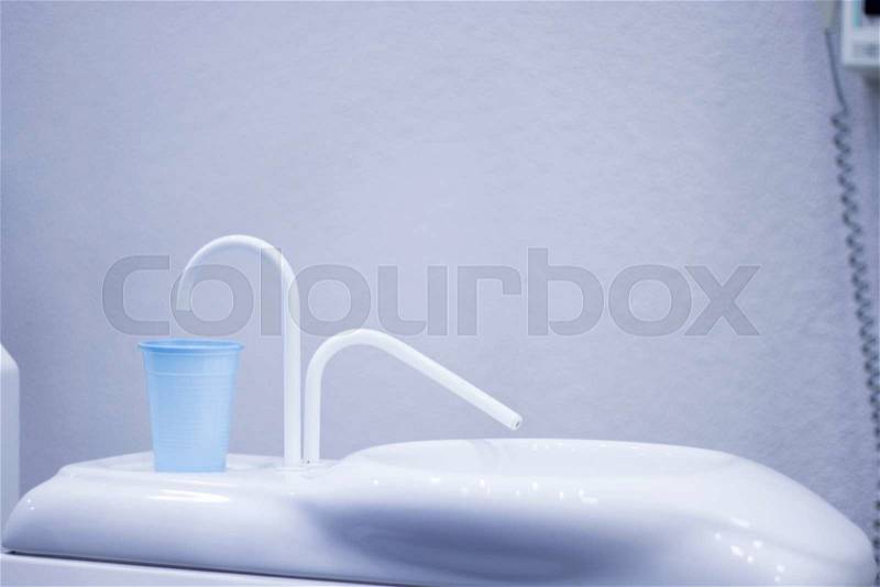 Dentist\'s chair and water wash mouth rinse and cup in hospital clinic, stock photo