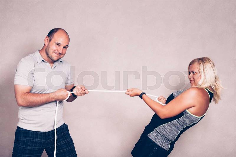 Positive confident sporty man and woman pulling a rope. Competition, confidence and effort concept, stock photo