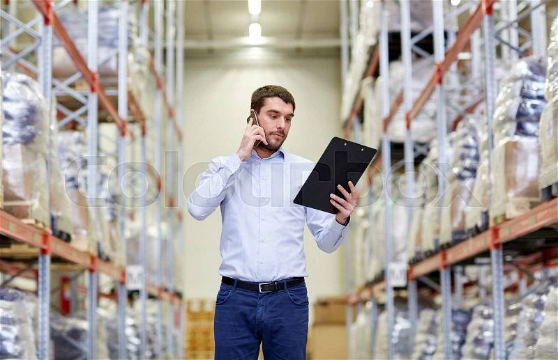 Wholesale, logistic, business, export and people concept - businessman with clipboard calling on smartphone at warehouse, stock photo