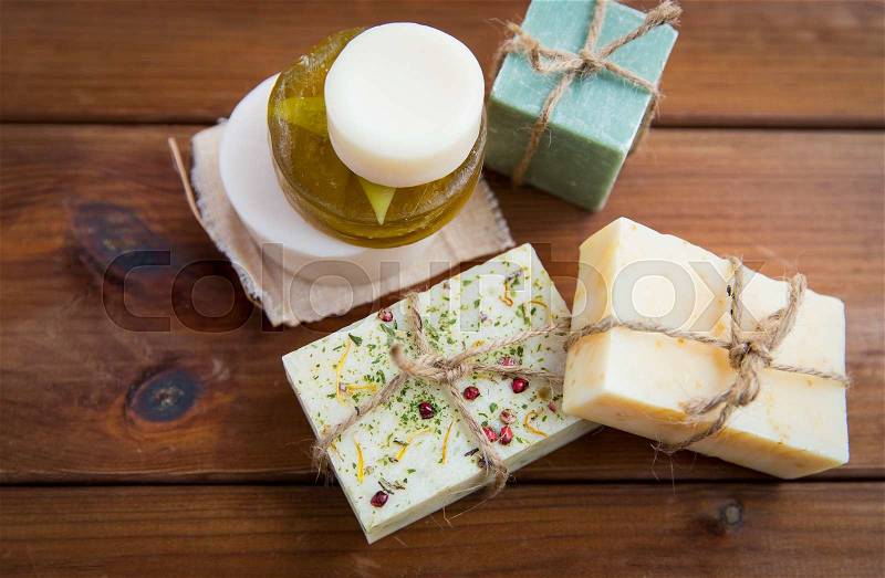 Beauty, spa, body care, bath and natural cosmetics concept - close up of handmade soap bars on wooden table, stock photo