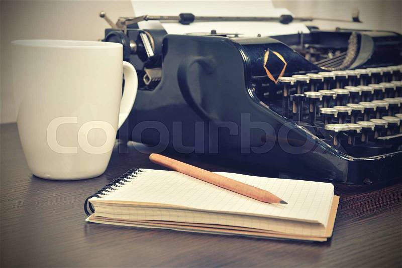 Blank notebook, cup and vintage typewriter on the writer\'s desk, stock photo