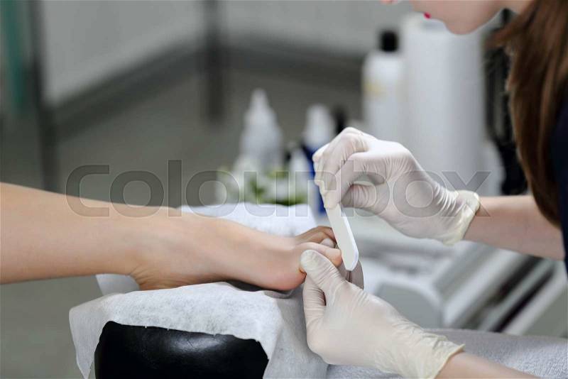 Working with the nail file big toe of clients leg. Service pedicure at the beauty salon, stock photo