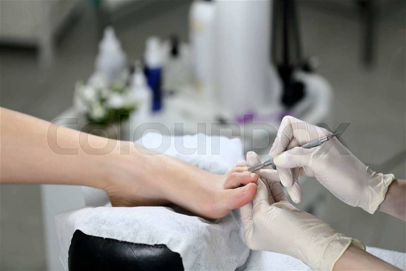 Woman receiving cuticle in manicure pedicure salon, stock photo