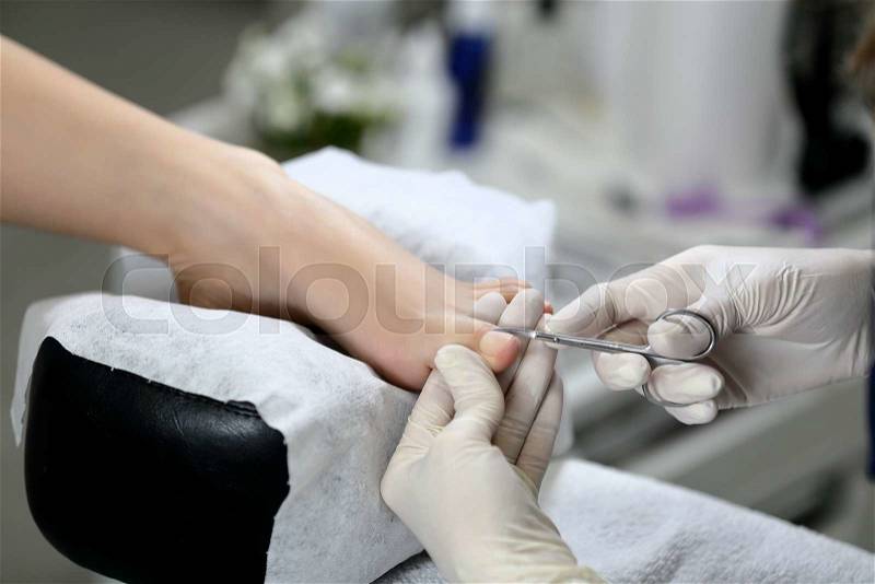 Cutting cuticle on foot, nail scissors. Pedicure, stock photo