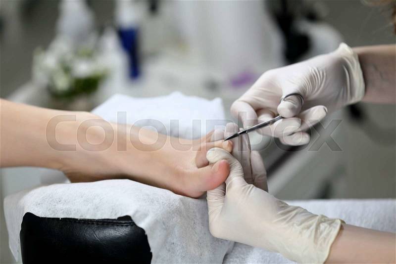 Close up Cutting cuticle on foot, nail scissors. On backgroun of flower and equipment for Pedicure process, stock photo