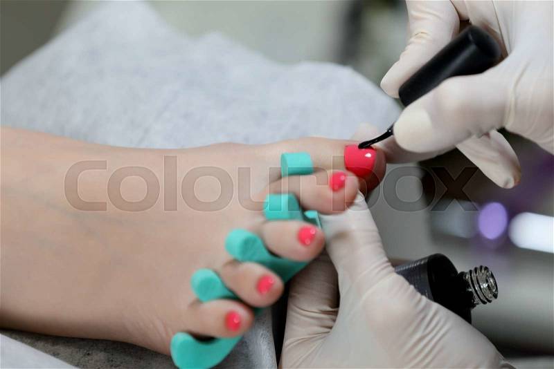 Gel pedicure. Pink color on the nails and white gloves of master, stock photo