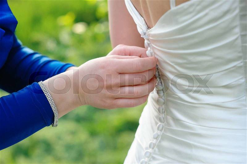 Bridesmaid is helping the bride to dress in weddihg day, stock photo