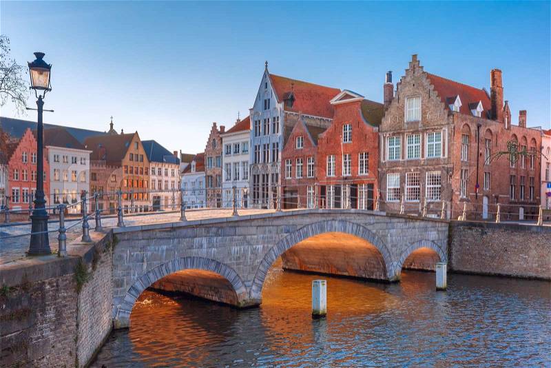 Scenic city view of Bruges canal with beautiful medieval colored houses and sunny bridge in the morning, golden hour, Belgium, stock photo