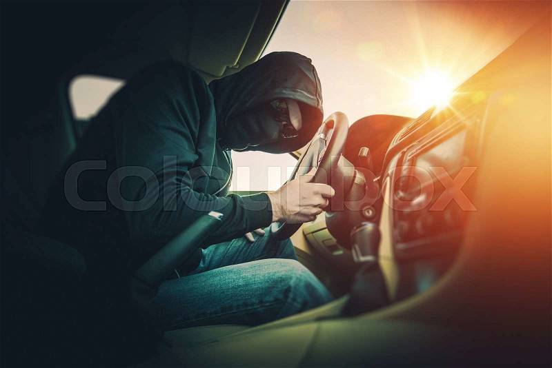 Car Thief in a Black Mask and Black Glasses. Car Thief Inside the Modern Car, stock photo