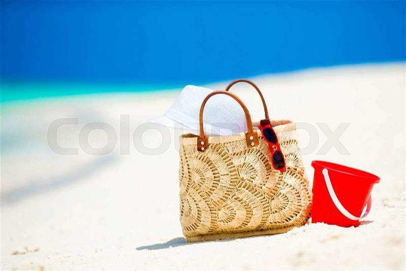 Beach accessories - straw bag, white hat and red sunglasses on the beach, stock photo