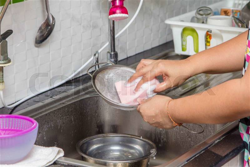 Women washing the sieve in sink, stock photo