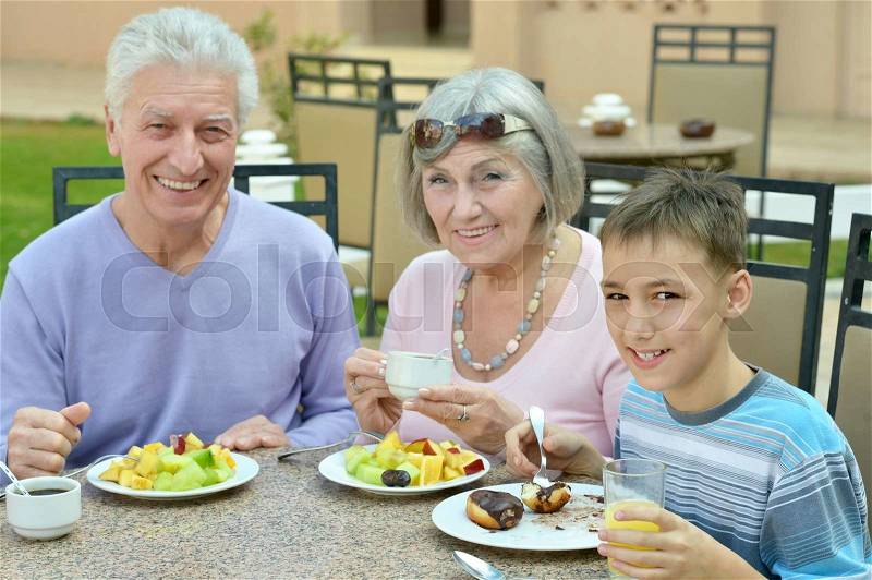 Grandparents with grandchild at breakfast on tropical resort, stock photo