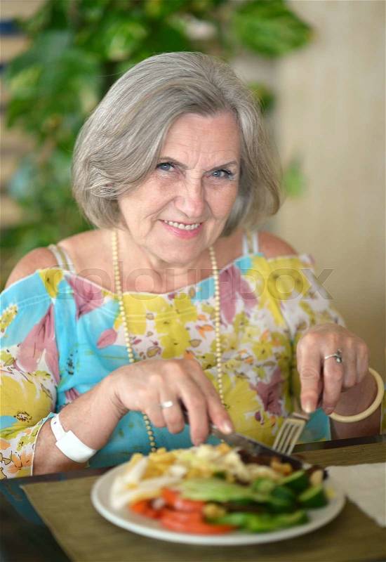 Elder woman with breakfast in a cafe, stock photo