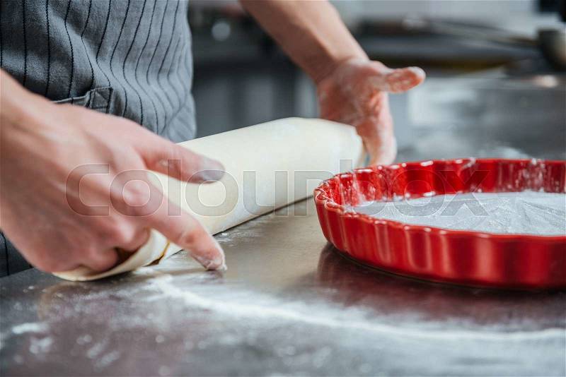 Hands of professional male chief cook making pie in baking pan on the kitchen, stock photo