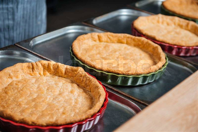 Close up of cooked pie bases in baking pans on the kitchen, stock photo