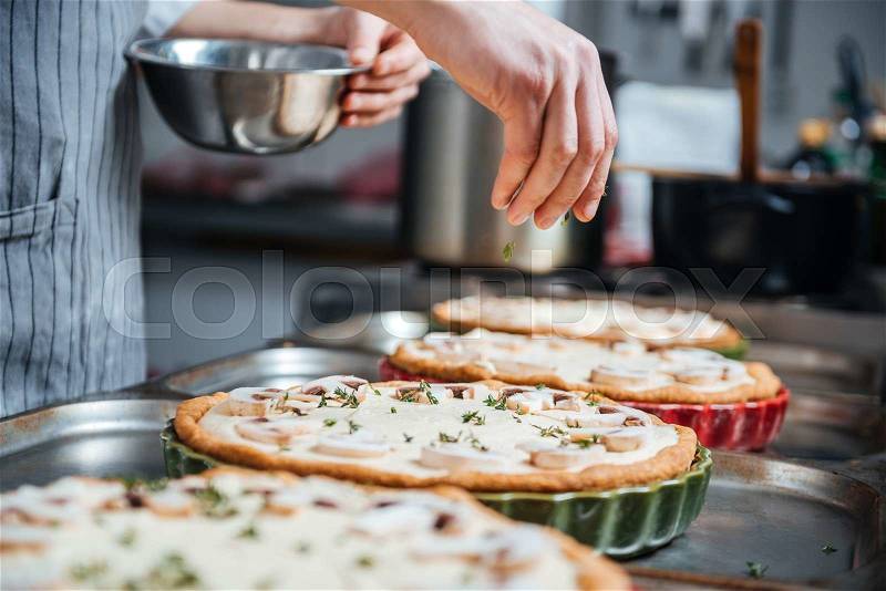 Hand of cook adding herbs and cooking pie on the kitchen, stock photo