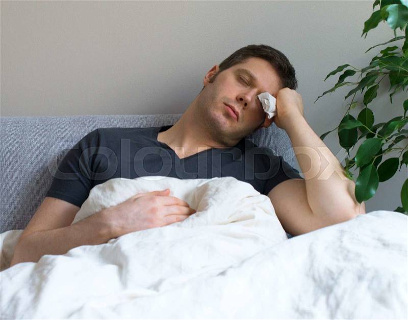 Sick man lying in the bed with fever, stock photo
