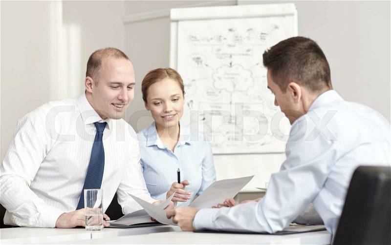 Business, people and teamwork concept - smiling business team with papers meeting in office, stock photo