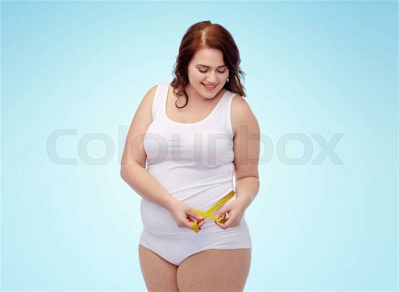Weight loss, diet, slimming, size and people concept - happy young plus size woman in underwear measuring tape over blue background, stock photo