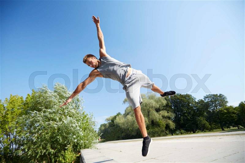 Fitness, sport, parkour and people concept - young man jumping in summer park, stock photo