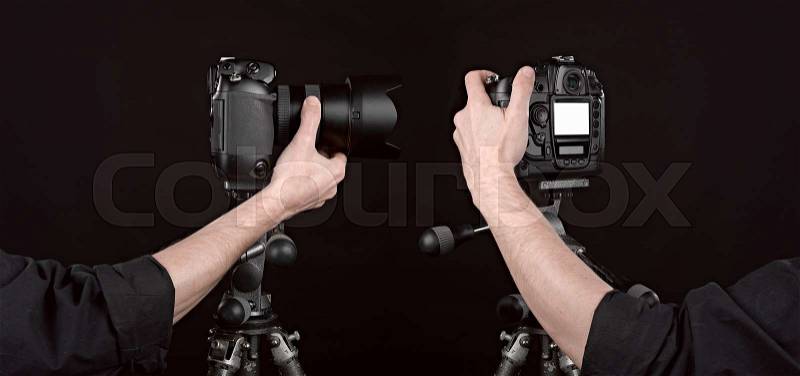 Two angle of Black digital camera on black background with photographer hand pushing the button, stock photo