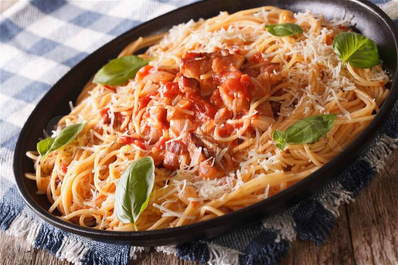 Italian Food: Spaghetti with Amatriciana Sauce, cheese and basil close-up on a plate on the table. horizontal , stock photo