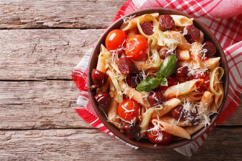 Penne pasta with sausage, leeks, cheese and tomato in a bowl on the table. horizontal view from above , stock photo