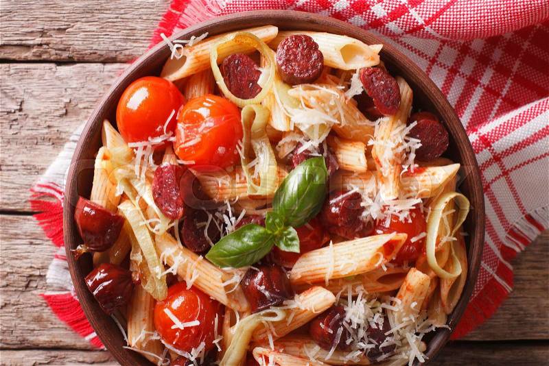 Pasta with sausage, leeks, cheese and tomato close up in a bowl on the table. horizontal view from above , stock photo