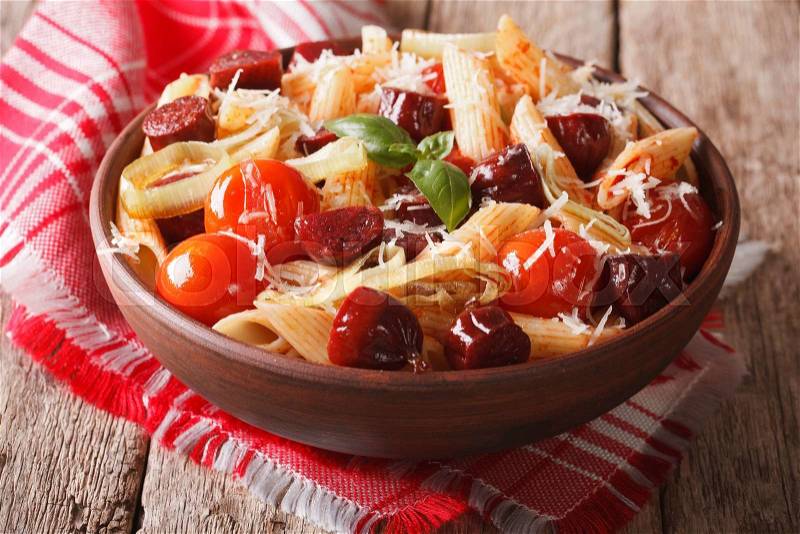 Pasta with sausage, leeks, cheese and tomato close up in a bowl on the table. horizontal , stock photo