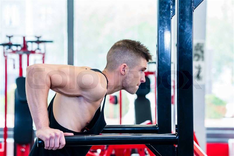 Man training dips in fitness center or gym training his upper arms and triceps, stock photo