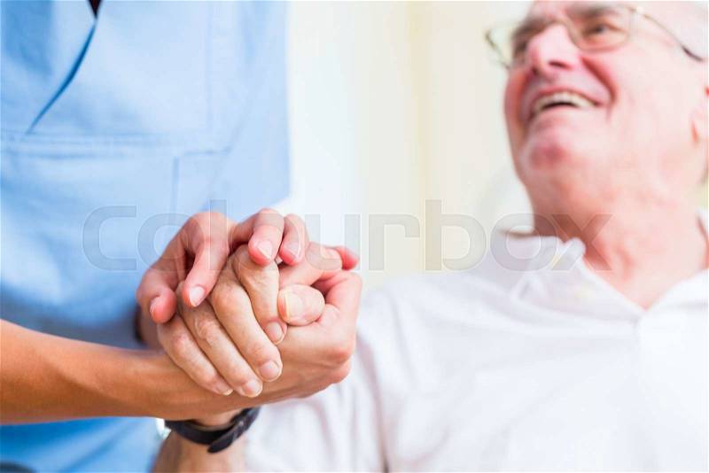 Nurse holding hand of senior man in rest home, stock photo