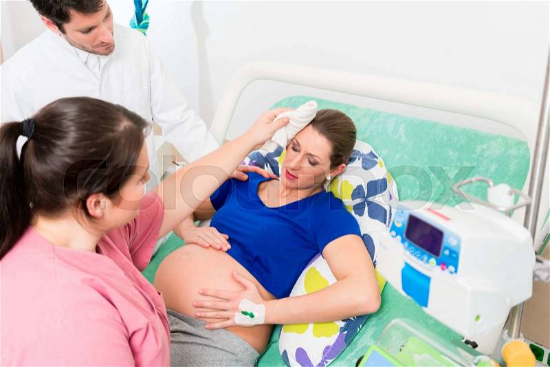 Pregnant woman in labor room with doctor and nurse, stock photo