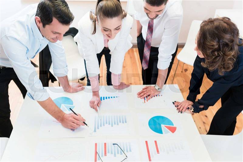Financial consultants in bank analyzing data and discussing graphs, stock photo