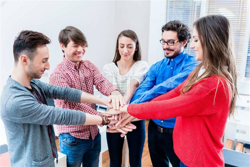 Students in university or college cling together stacking hands as a team, stock photo