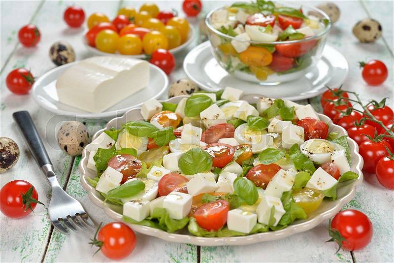 Vegetarian salad with cherry tomatoes, eggs and cheese on white background, stock photo